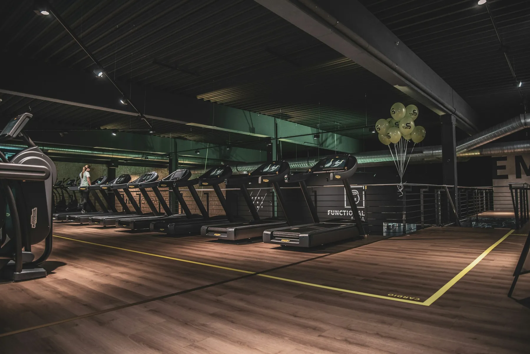 A gym with a wooden floor and machines